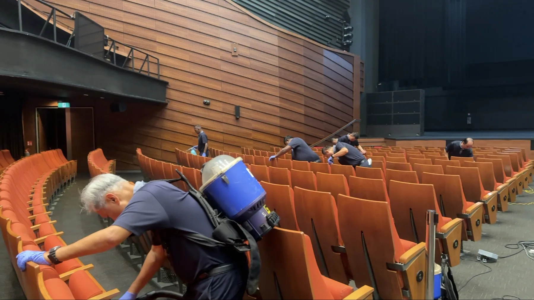 Crusade technicians vacuuming auditorium seating with backpack units